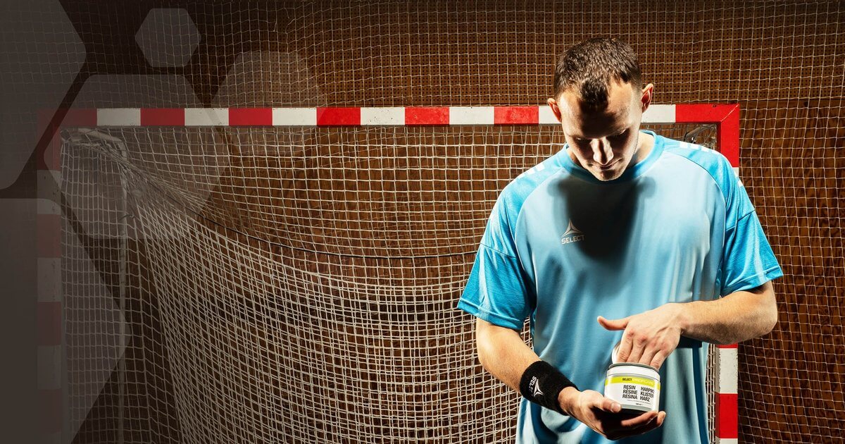Handbalist aplică clister Select pe mâini în fața porții de handbal